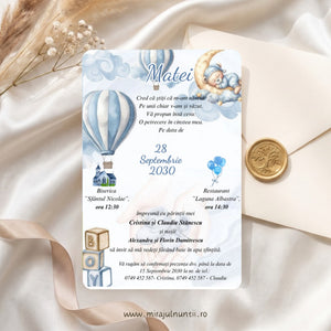 Invitație de botez cu ursuleț care doarme pe lună, baloane cu aer cald în dungi bleu, nori în acuarelă și cuburi BOY, numele Matei scris caligrafic, lângă un plic crem cu sigiliu auriu, cod Magnific B.20-20020
