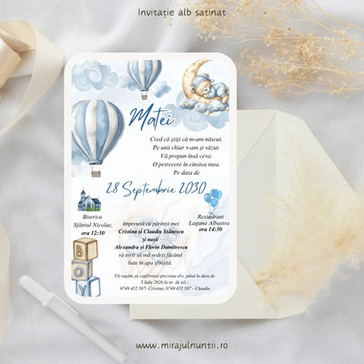Invitație de botez cod Magnific B.20-20020 pe carton alb satinat, cu ursuleț care doarme pe semilună, baloane cu aer cald în dungi bleu, nori în acuarelă și cuburi BOY.