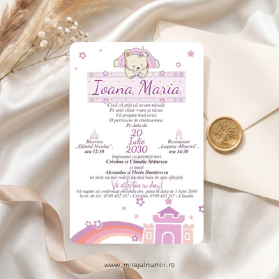 Invitație de botez tipărită B. 3507 pe carton alb: ursuleț cu glugă roz de unicorn așezat pe banderola roz cu numele Ioana Maria, textul invitației la mijloc și castel roz-lila cu curcubeu jos