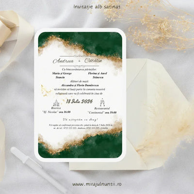 Invitație de nuntă cod Magnific C.4 pe carton alb satinat, cu acuarelă verde smarald și sclipici auriu sus și jos, lângă un plic crem și ierburi pampas.