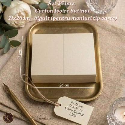 Set 25 bucăți carton ivoire satinat 250g biguit pentru meniuri nuntă tip carte, dimensiune 21x26 cm, așezat pe tavă aurie lângă accesorii de scris.