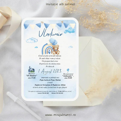 Invitație de botez cod Magnific B.12-20012 pe carton alb satinat, cu stegulețe albastre, nori pufoși și ursuleț lângă un curcubeu bleu.