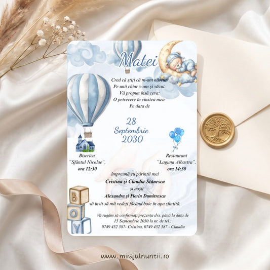 Invitație de botez cu ursuleț care doarme pe lună, baloane cu aer cald în dungi bleu, nori în acuarelă și cuburi BOY, numele Matei scris caligrafic, lângă un plic crem cu sigiliu auriu, cod Magnific B.20-20020