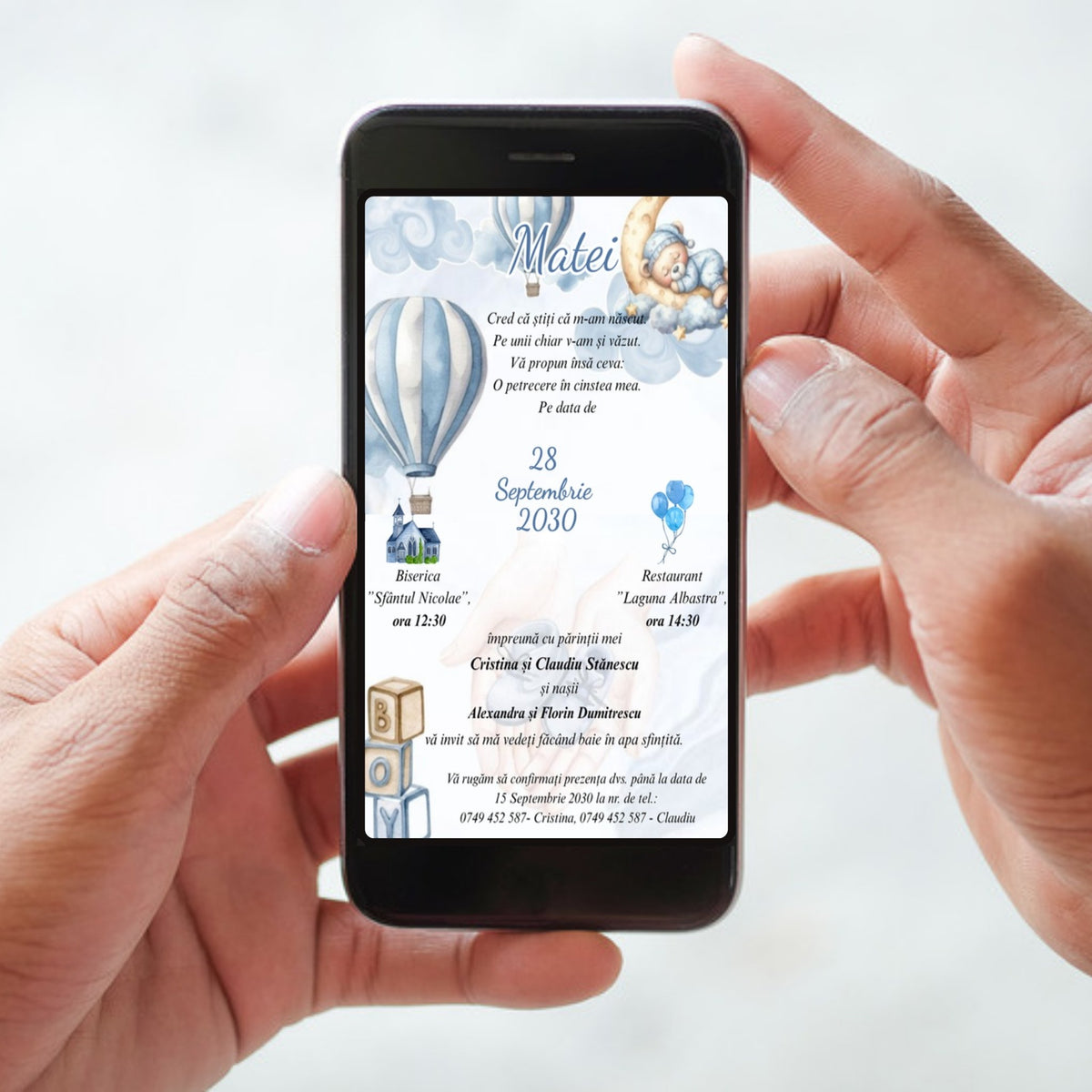 Invitație digitală de botez cod Magnific B.20 pe ecranul unui telefon ținut în mâini: ursuleț care doarme pe lună, baloane cu aer cald în dungi bleu, numele Matei scris caligrafic