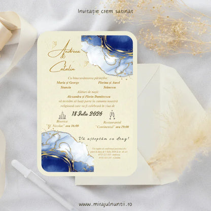 Invitație de nuntă cod Magnific C.3 pe carton crem satinat, cu acuarelă bleumarin, vene aurii și text auriu, lângă un plic crem.