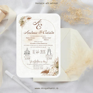 Invitație de nuntă cod Magnific C.30 pe carton alb satinat, cu pampas, orhidee albe și chenar arcuit auriu, în teracotă și crem, lângă un plic crem.