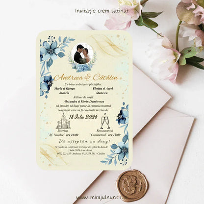 Invitație de nuntă florală cod Magnific C.5, cu flori albastre, tușe aurii și numele mirilor scrise caligrafic.
