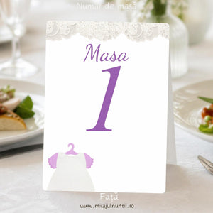 Număr de masă botez, față, cu bandă de dantelă albă sus, „Masa 1” cu lila și rochiță albă de botez cu mânecuțe roz-lila pe umeraș jos în stânga, cod B. 7608