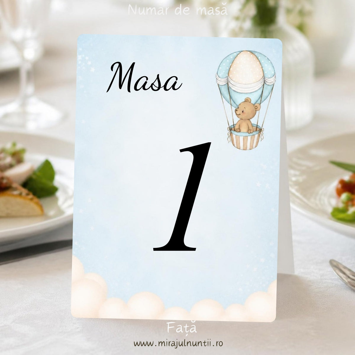 Număr de masă botez „Masa 1”, fața, cu ursuleț în balon cu aer cald în dreapta sus și nori pufoși jos, pe cer bleu pal în acuarelă, carton alb satinat – cod Magnific B.3-20003