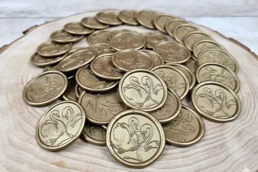 Sigilii din ceară aurie cu două lebede față în față, așezate pe o felie de lemn
